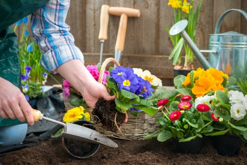 Gardener maintaining flowerbeds and mowing a small communal lawn in Peckham